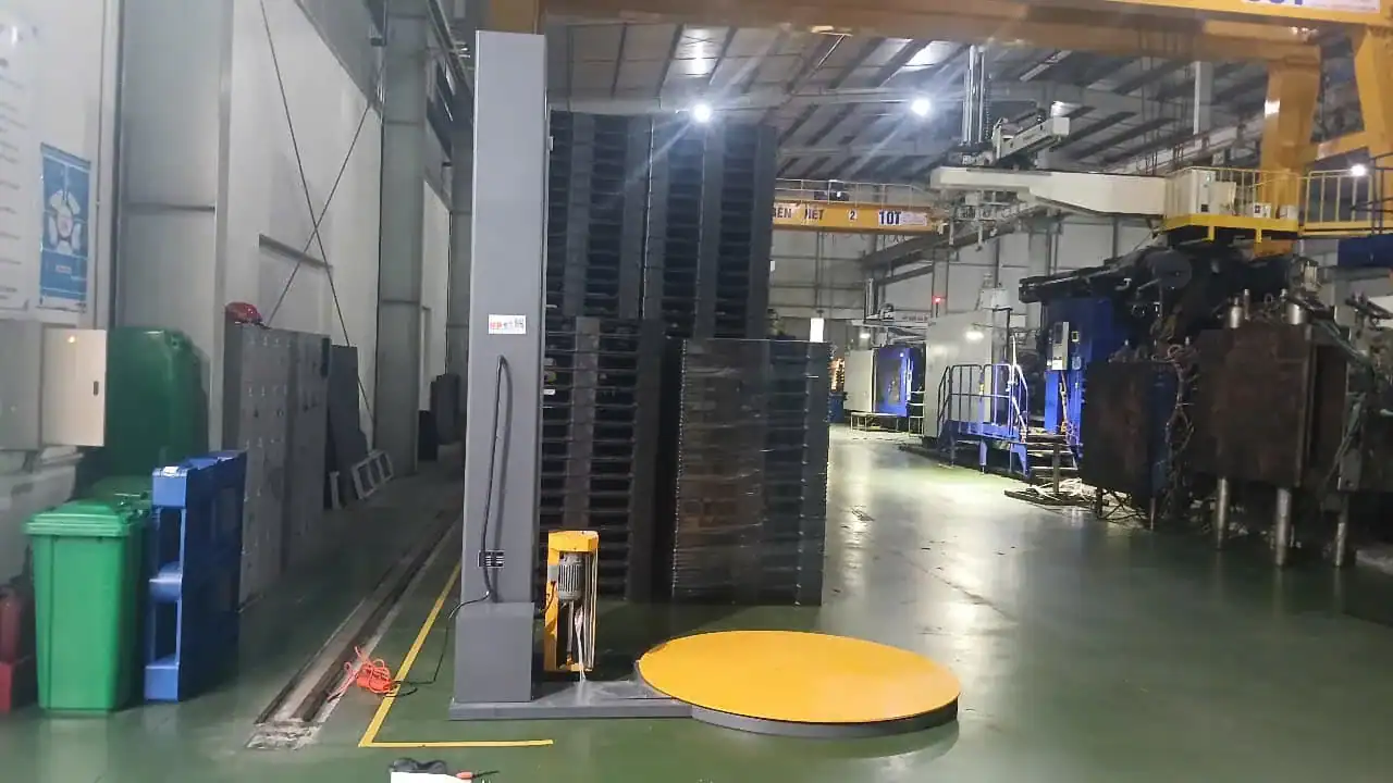 Turntable pallet wrapping machine beside a production line in a customer's factory