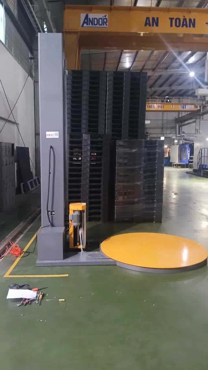 Máy quấn ICDT1650F cạnh chồng pallet nhựa trong xưởng, phía trên có cầu trục