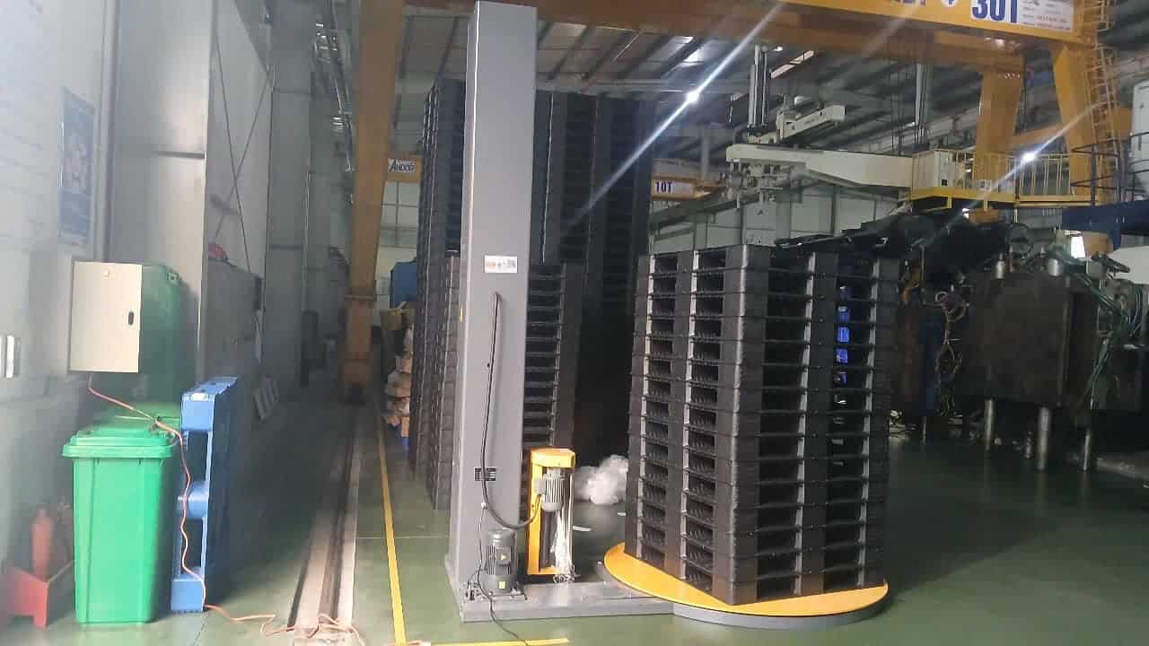 Chồng pallet nhựa trên mâm xoay của máy quấn pallet trong xưởng sản xuất