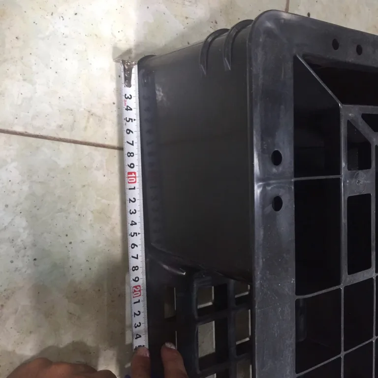 Đo chiều cao chân pallet nhựa đen bằng thước cuộn