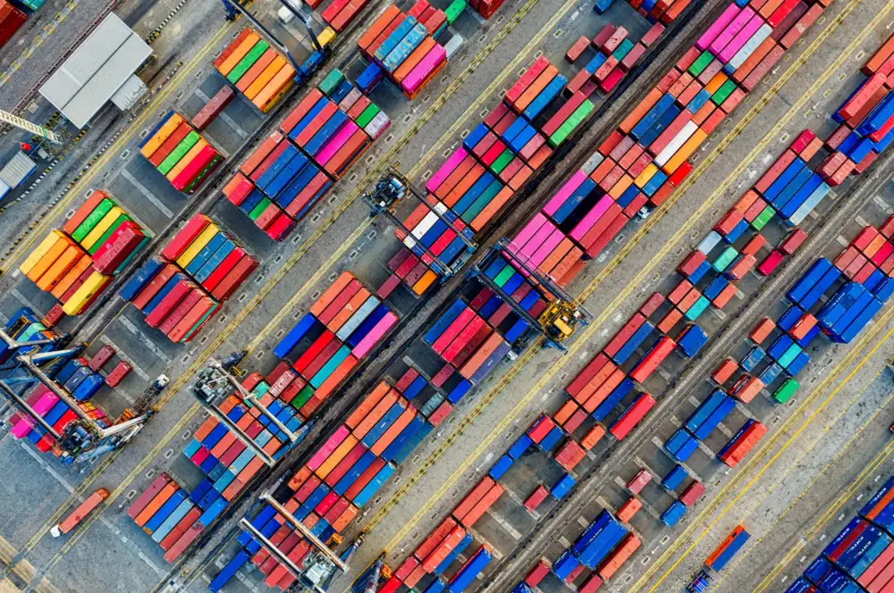 Aerial view of a container yard at a seaport, with rows of containers waiting to be loaded