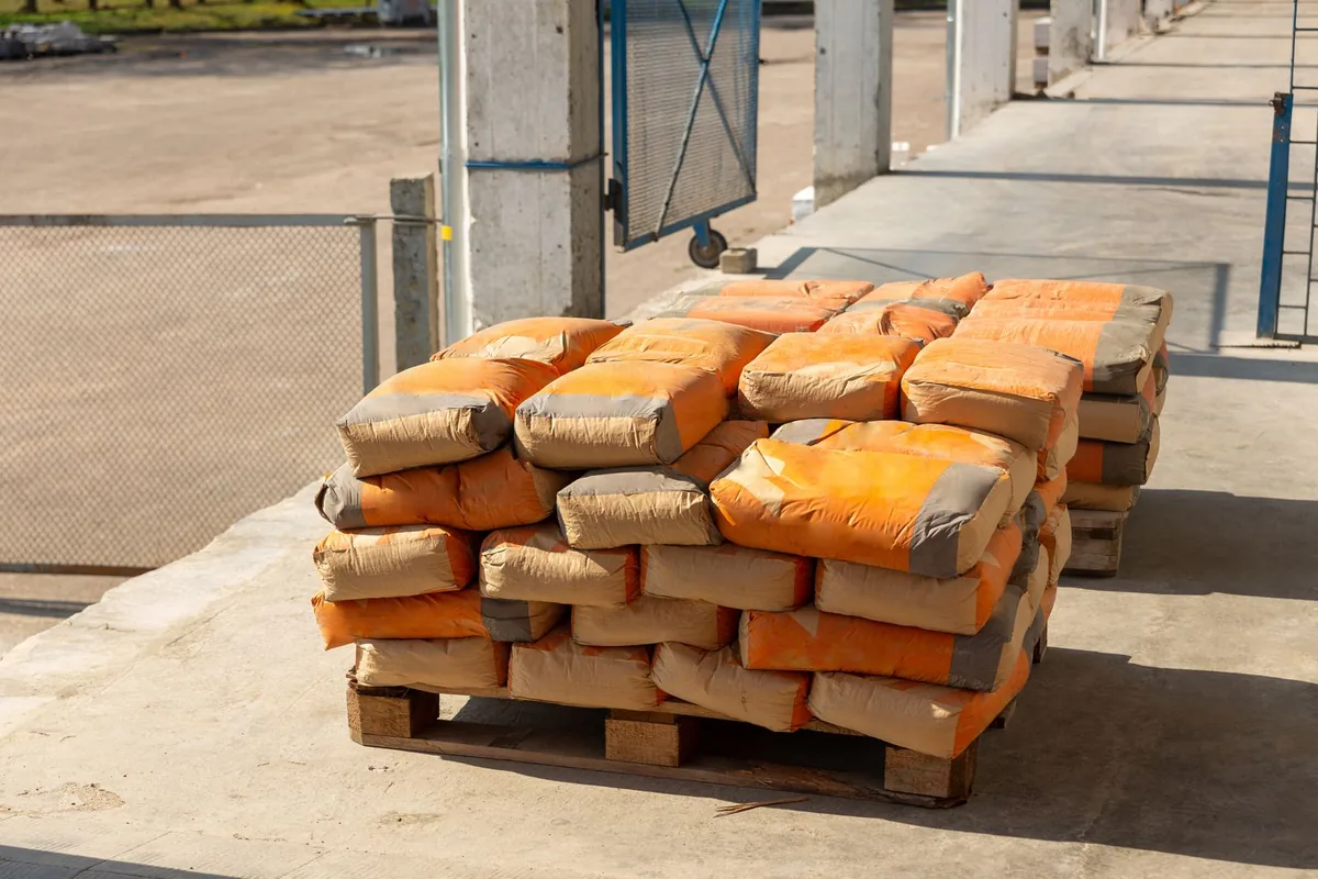 Bao xi măng xếp chồng trên một pallet gỗ đặt ngoài trời