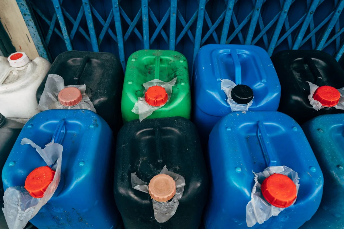 Nhiều can nhựa HDPE màu xanh, đen, trắng nắp vặn đỏ xếp sát nhau