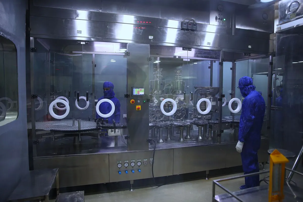 A worker in protective clothing operating a medicine filling line in a cleanroom
