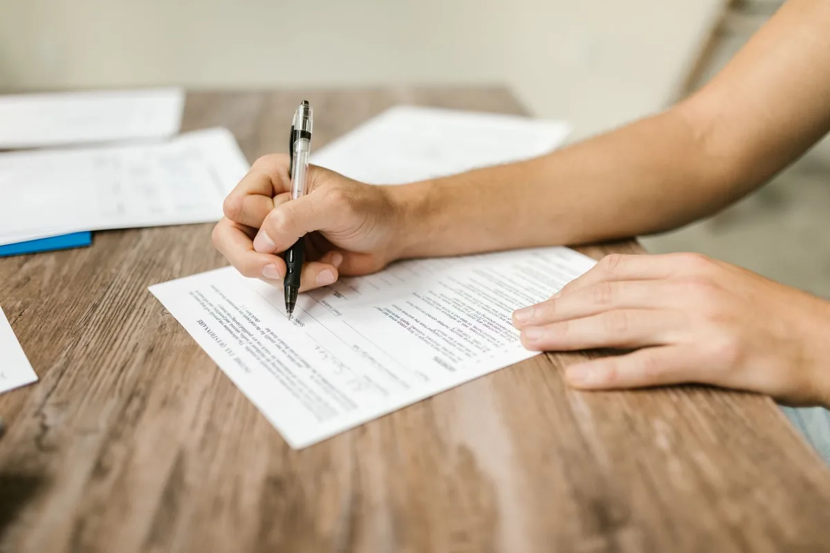 Người điền thông tin vào biểu mẫu trên bàn gỗ