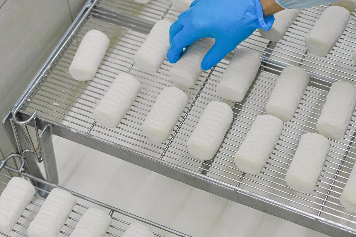Gloved hand inspecting product on a stainless steel mesh rack