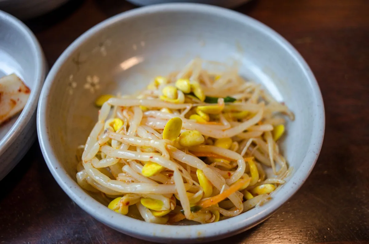 A bowl of mixed soybean sprouts, with yellow soybean heads