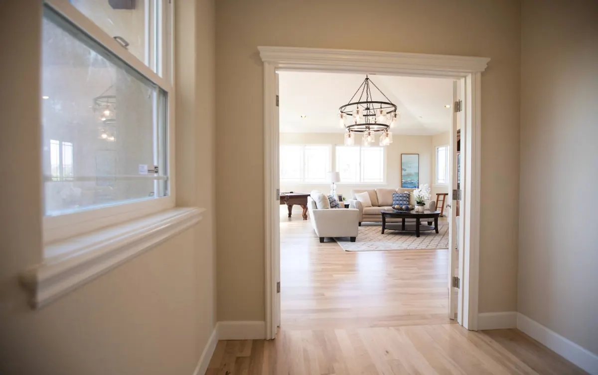 A hallway and living room with light-colored natural wood flooring