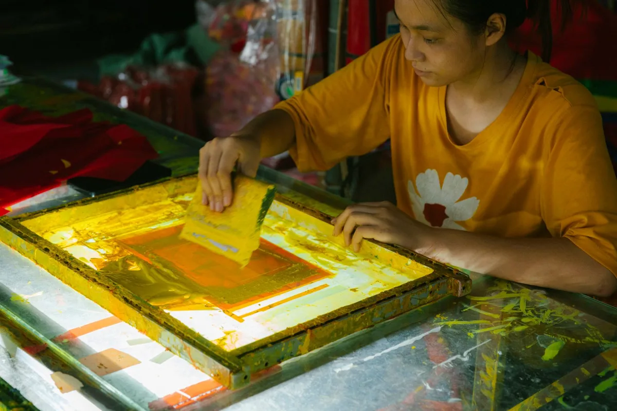 Thợ in kéo mực qua khung lưới in lụa