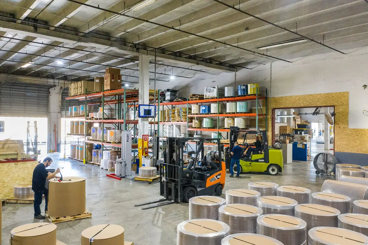 Forklift moving a large paper reel on a pallet in a warehouse