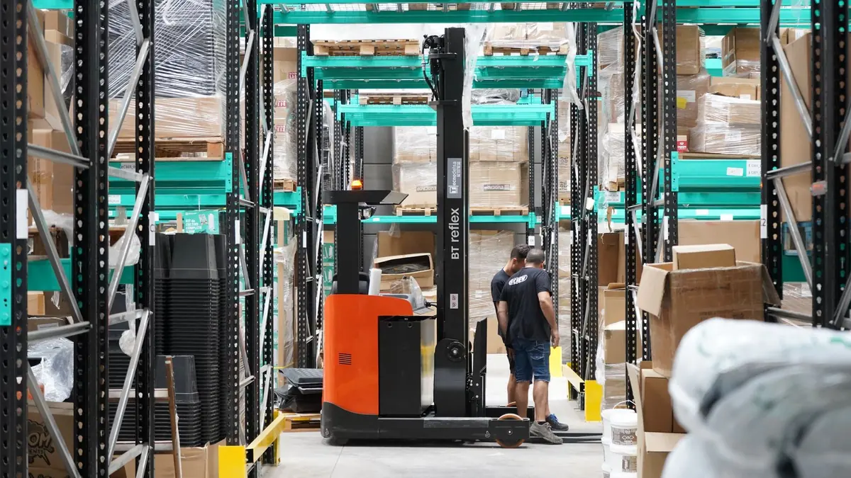 Stand-up forklift working between rows of selective racking in a warehouse