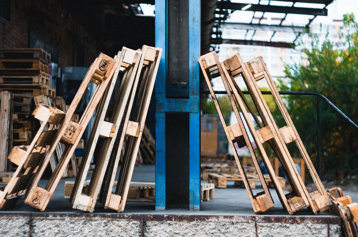 Các pallet gỗ cũ bị gãy nan dựng nghiêng chờ sửa