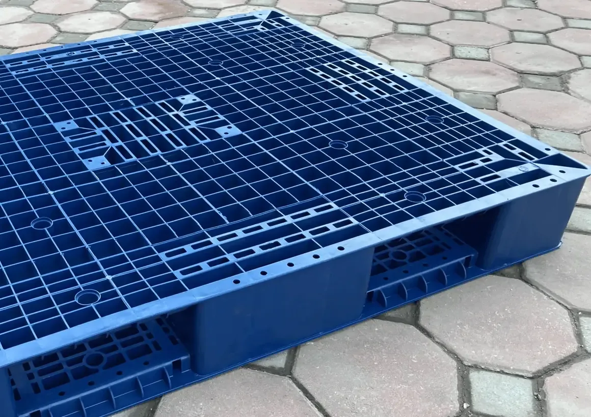 Góc pallet nhựa hai mặt màu xanh dương đặt trên nền gạch