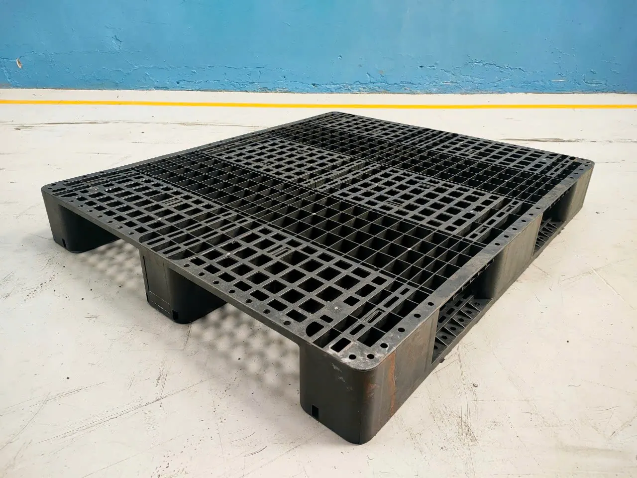 Black three-runner plastic pallet, 1300x1100x155 mm, with its runners visible from the side
