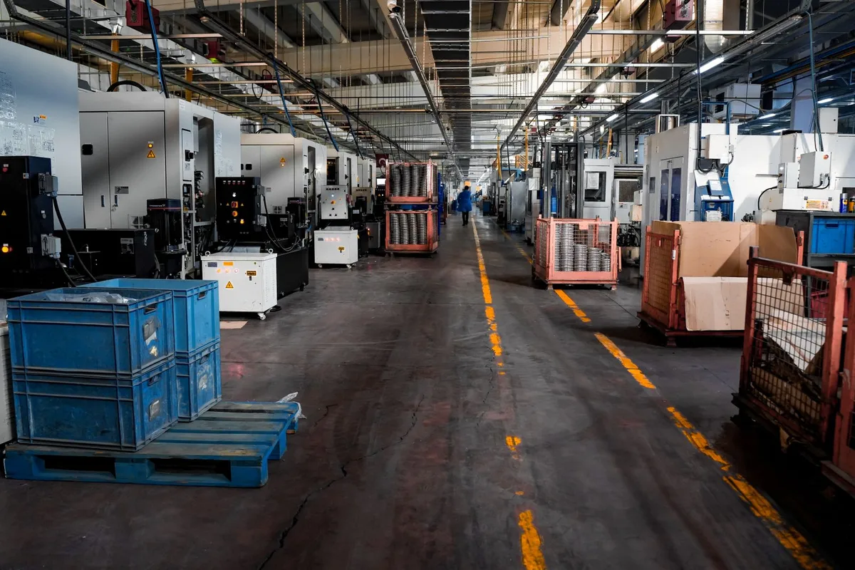 Blue plastic crates stacked on blue plastic pallets in a factory aisle