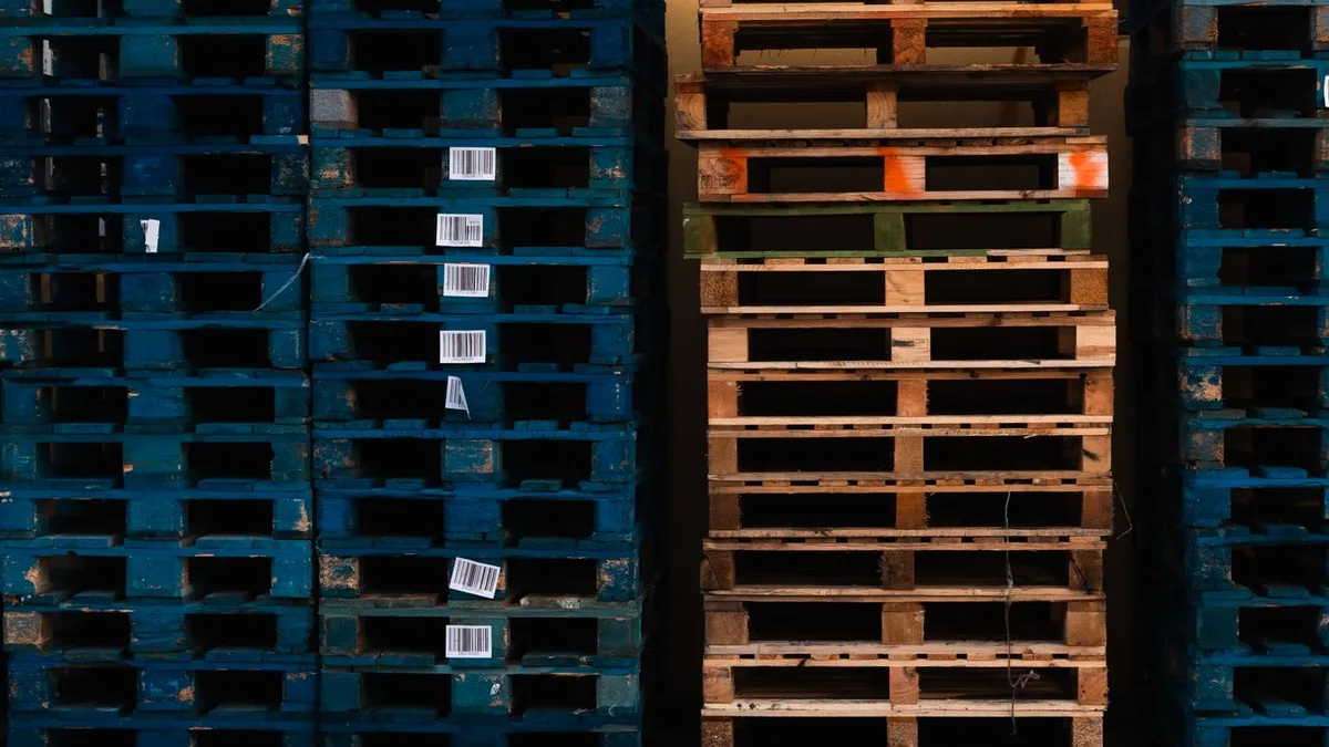 Chồng pallet nhựa xanh và pallet gỗ xếp cạnh nhau trong kho