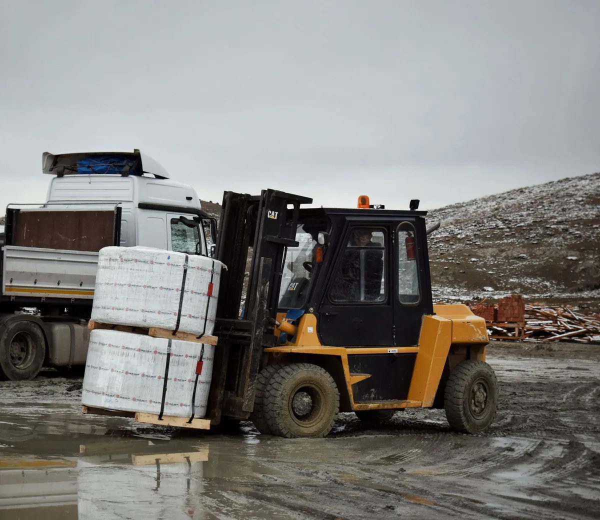 Forklift loading a package on a pallet onto a truck during transport