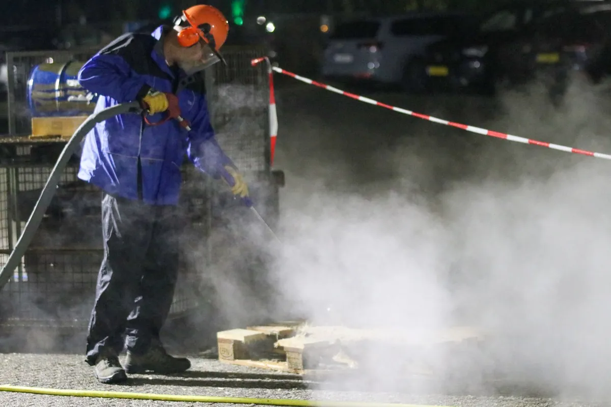 Worker cleaning a pallet with a high-pressure washer