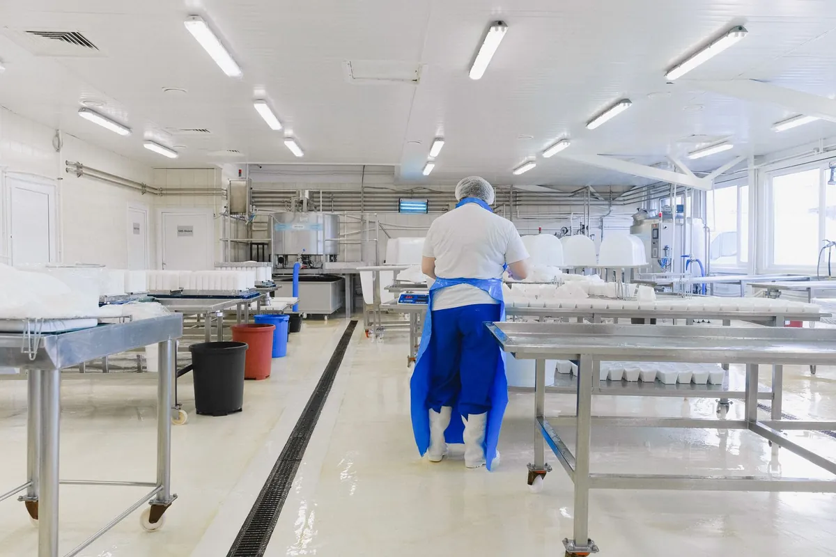 Worker cleaning a clean food production area with a dry floor, following procedure