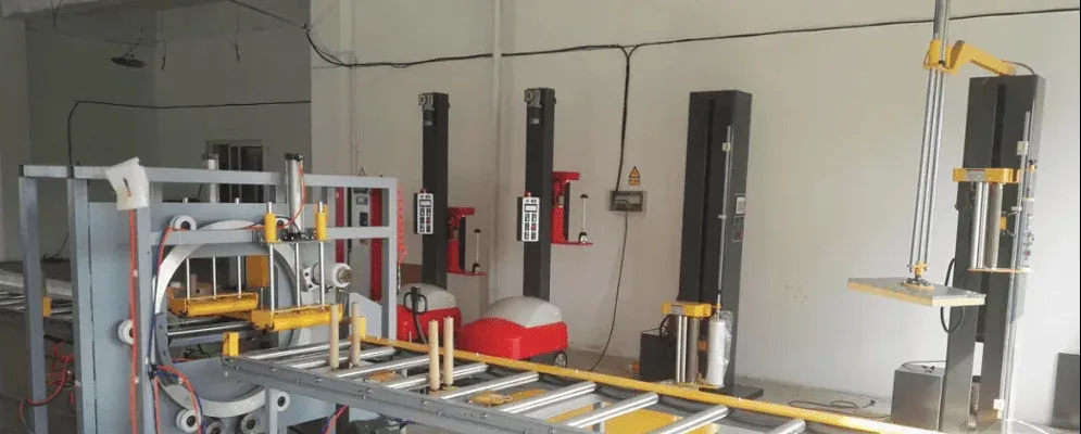 Máy quấn nằm ngang ICD với băng chuyền con lăn trong xưởng, bên cạnh các máy quấn pallet