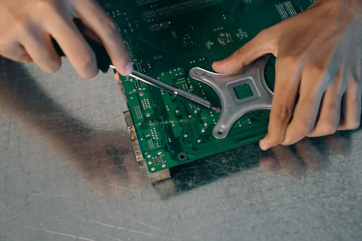 Two hands holding a screwdriver working on a blue computer circuit board