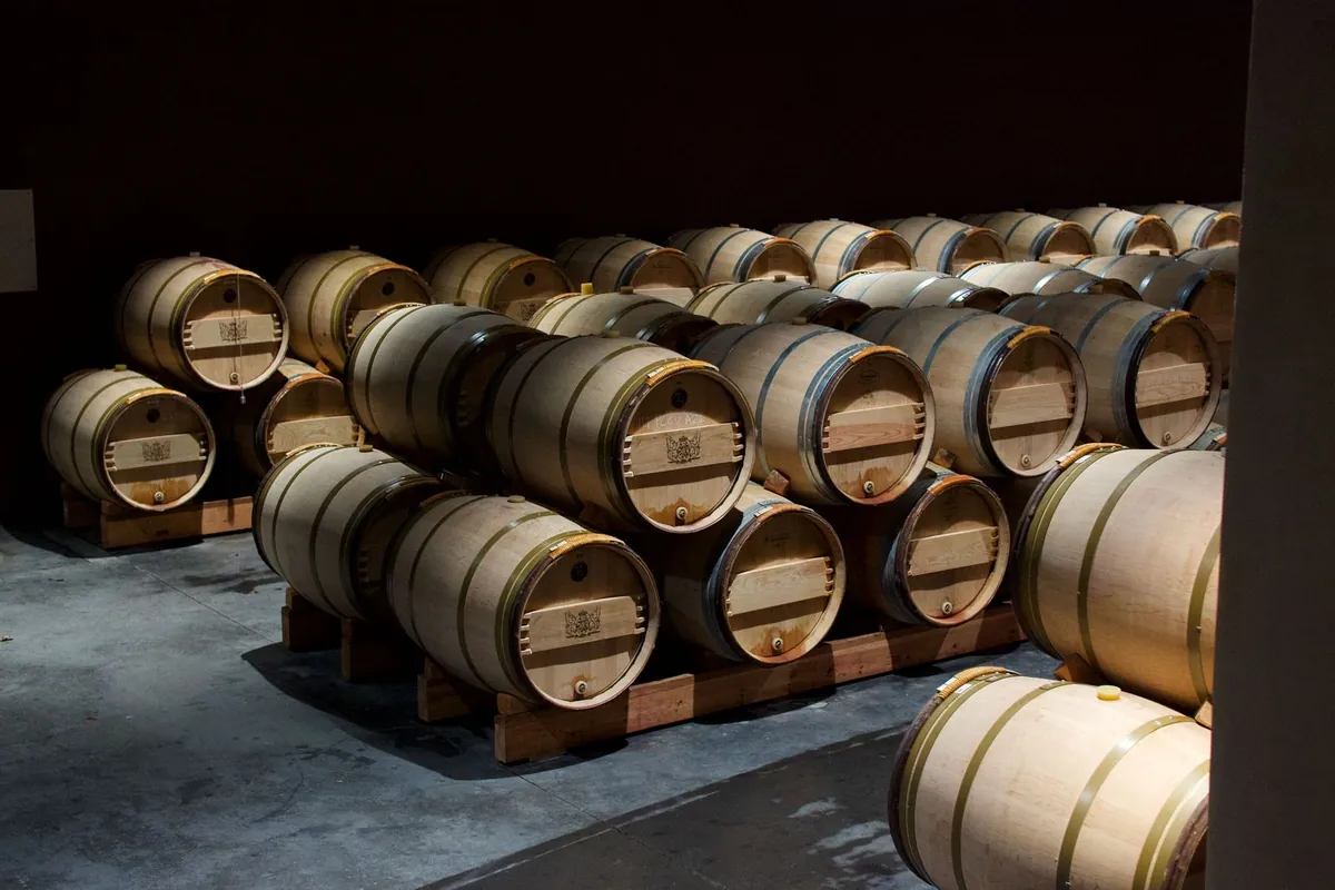 Oak wine barrels stacked on wooden racks in a wine cellar